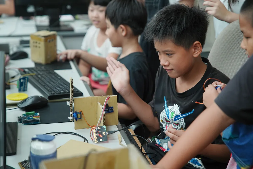 孩子們盯著螢幕,用 Microbit 控制自己用紙箱做的智慧家園